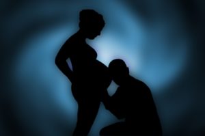 Pregnant woman and man with ear to her belly